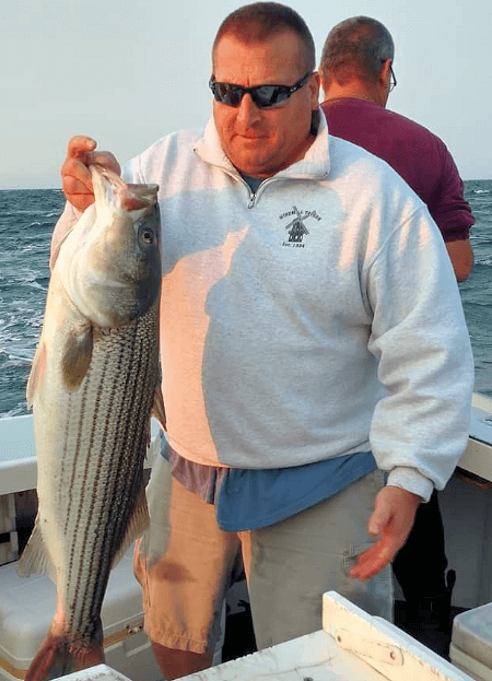Angler holding up another nice Block Island striper.